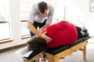 A chiropractor adjusts a patient's neck and upper back on a chiropractic table.